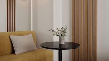 Quarto moderno com sofá, mesa redonda com um vaso de flores e iluminação embutida na parede.