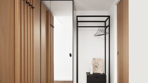 A modern room with a wooden wardrobe, a black metal shelf unit, and a wooden floor. - Bob W Münchner Freiheit (Munich)
