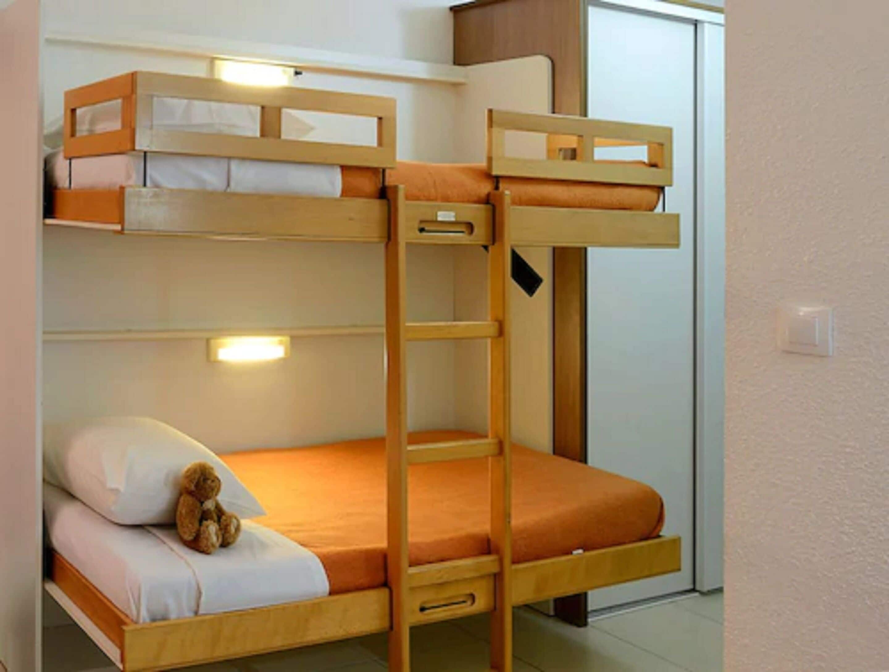 A bunk bed with a ladder and a teddy bear on the lower bunk.