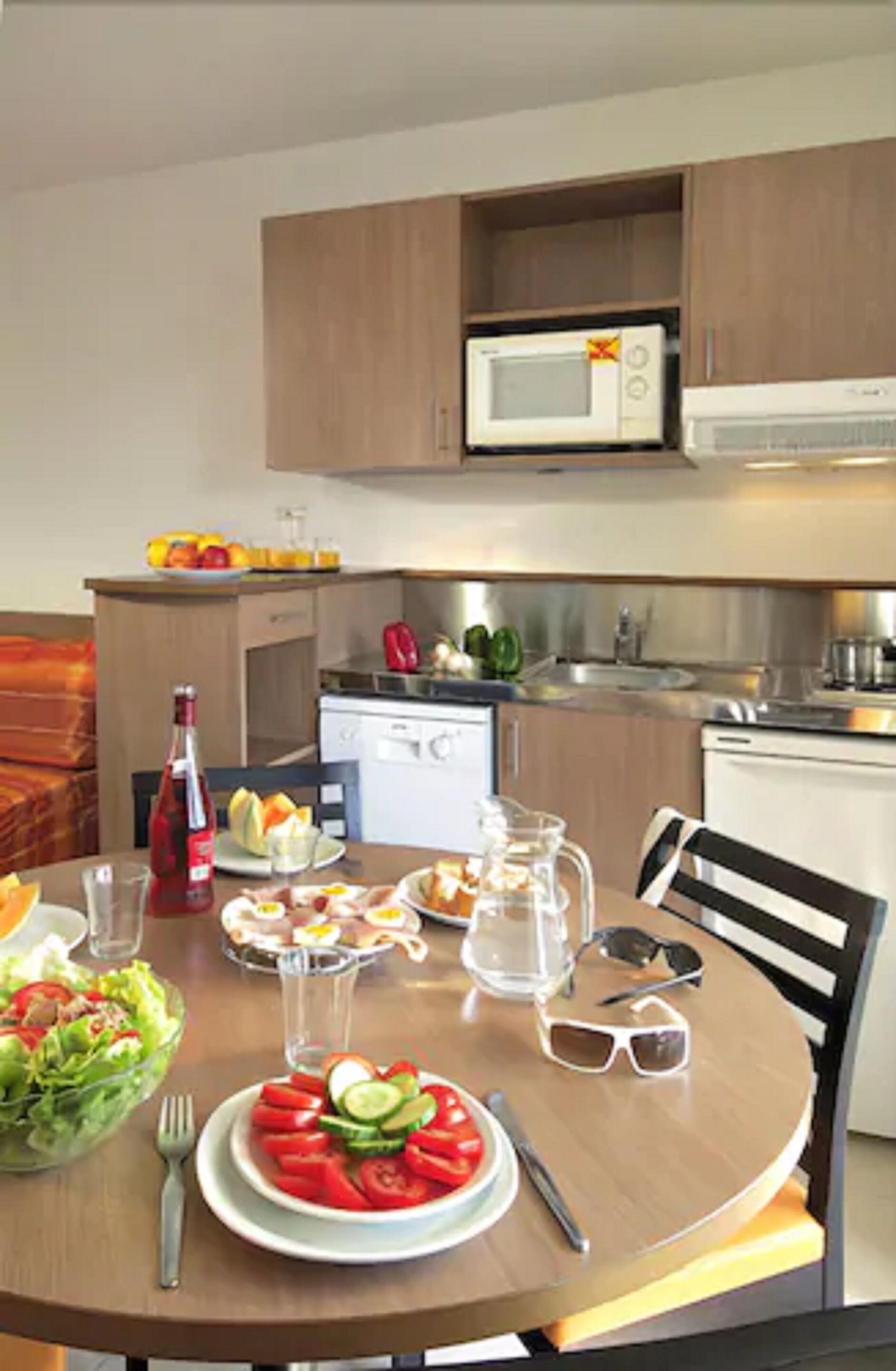 A dining area with a table set for a meal, a microwave above the counter, and a sink in the background.