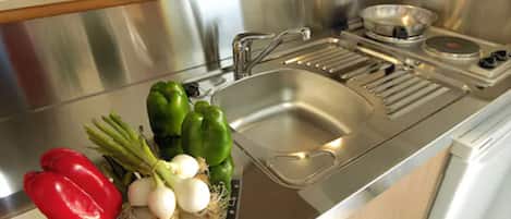A stainless steel kitchen with a sink, a cutting board, and fresh vegetables like bell peppers and onions.