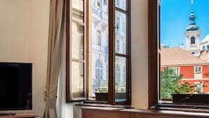 Ein Zimmer mit großem Fenster, Holzschränken, einem Fernseher und einer Zeitschrift auf einem Tisch.