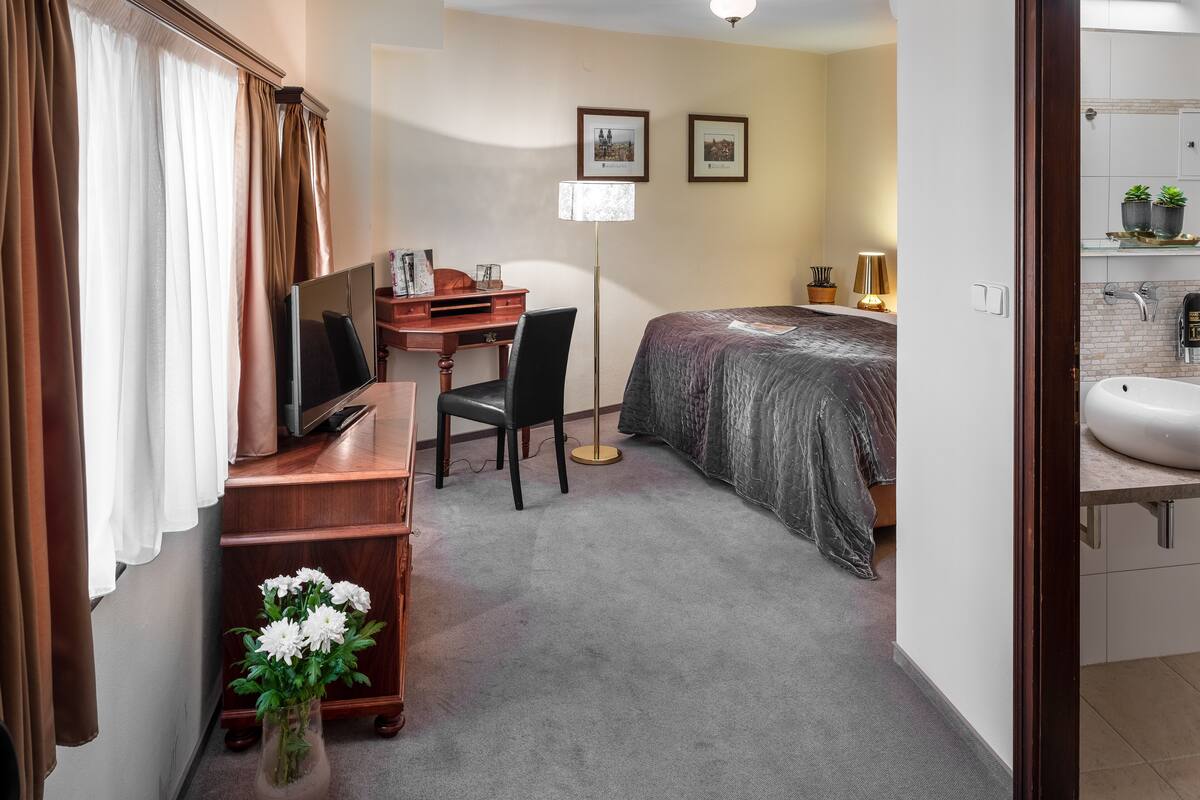 Habitación de hotel con escritorio, silla, cama y baño pequeño.
