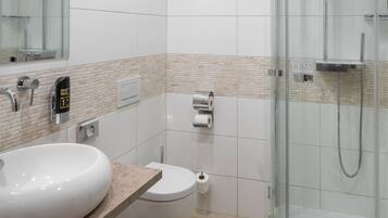 A modern bathroom with a glass-enclosed shower, a white sink, and a toilet.