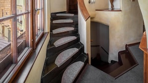 Eine Treppe mit hölzernem Geländer und Teppichstufen, die zu einer Zwischenebene führen.