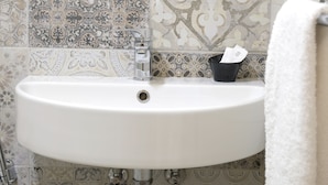 A bathroom with a white sink, a faucet, and a black cup with a tissue. - Residenza Le Rondini (Florence)