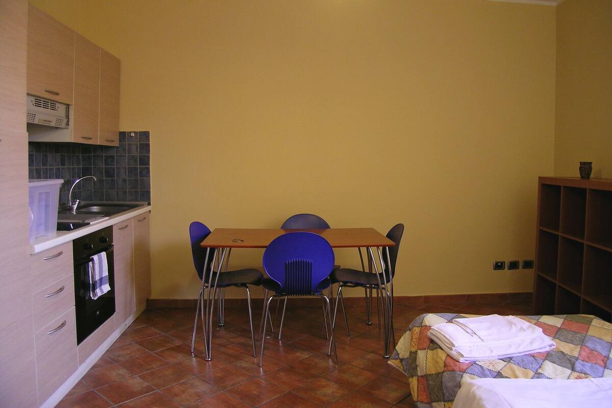 A compact kitchen with a dining table and chairs, a small oven, and a tiled backsplash.
