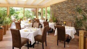 A restaurant with outdoor seating, stone walls, and potted plants. - Partaneshof (Merano)