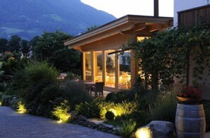 A modern, glass-enclosed outdoor dining area with a view of a mountain range. - Partaneshof (Merano)