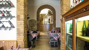 A restaurant with brick arches, tables with checkered tablecloths, and wine bottles on shelves. - Castelfidardo (Rome)