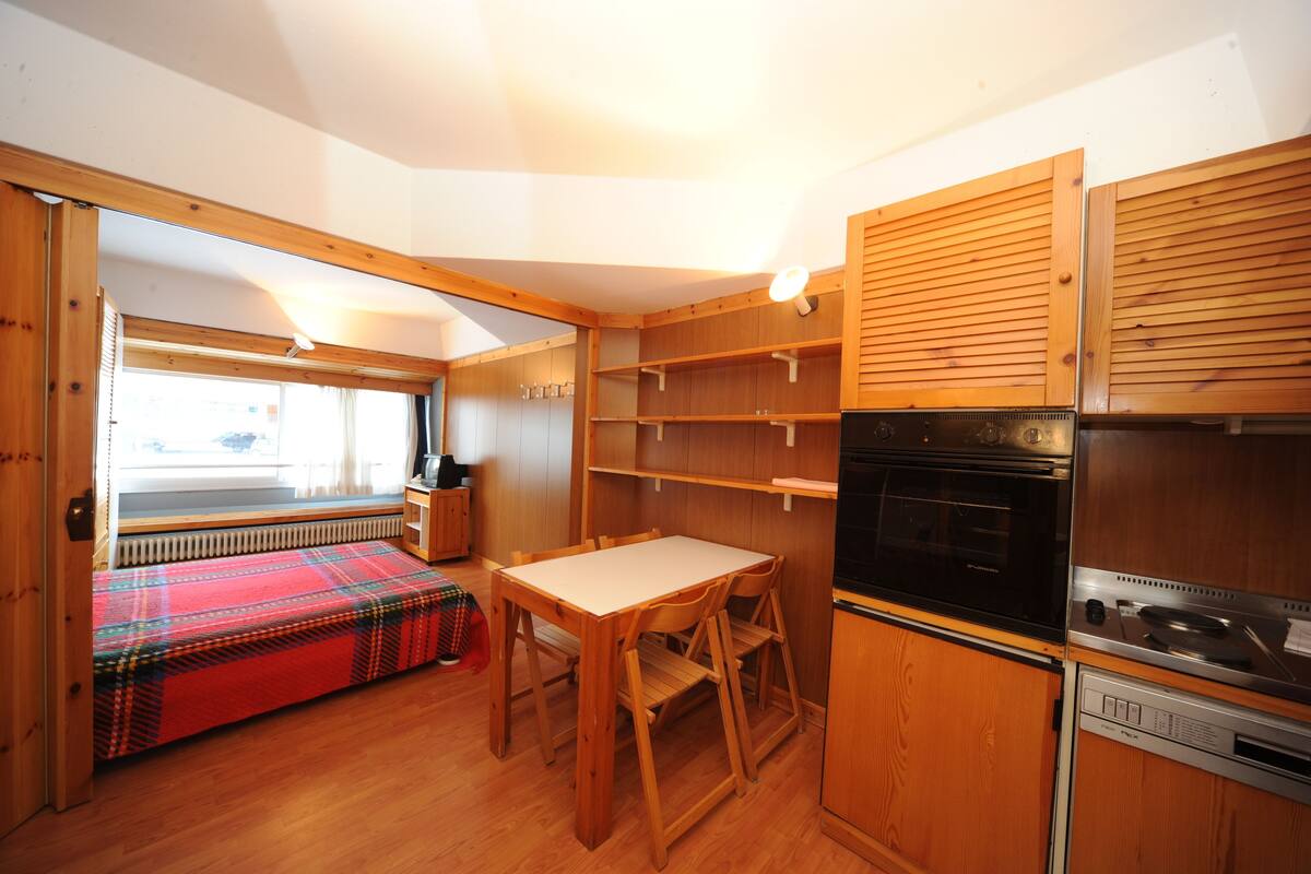 Una cocina compacta con armarios de madera, una mesa de comedor y un horno empotrado.
