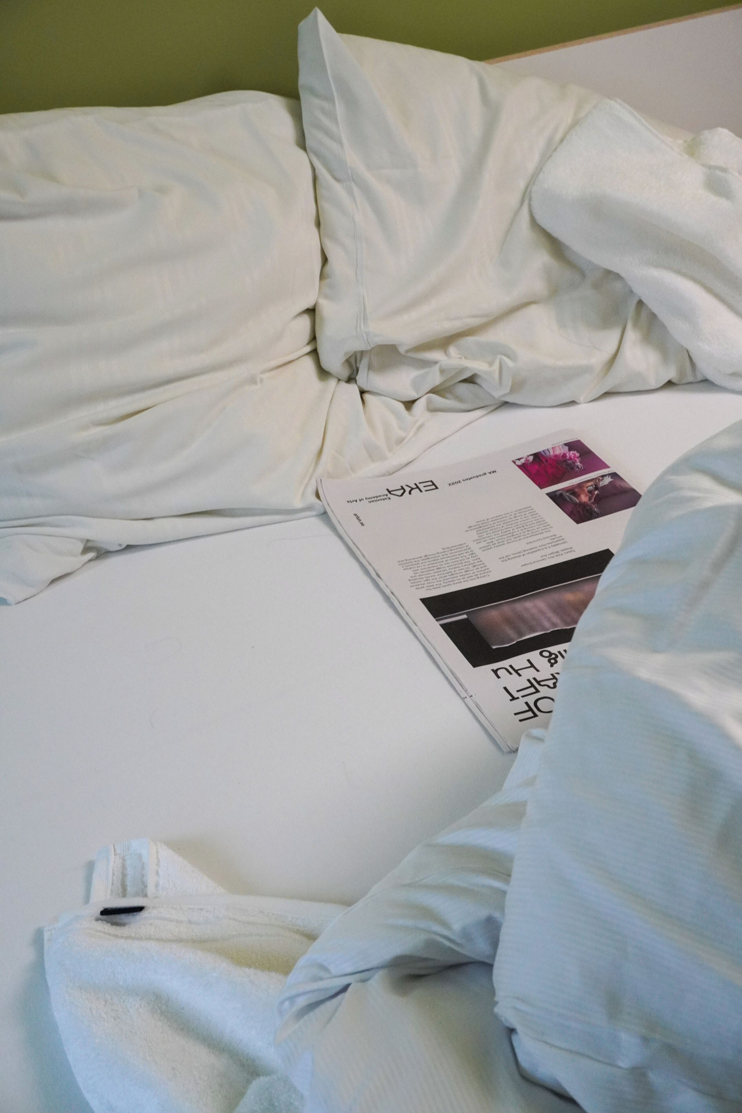 A neatly made bed with a magazine on it.