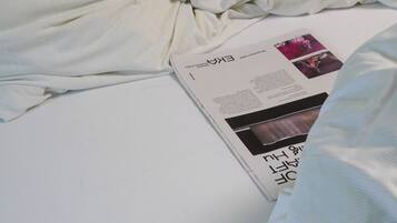 A neatly made bed with a magazine on it.