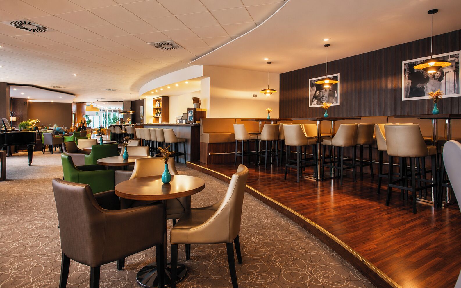 Un vestíbulo de hotel con mesas redondas, taburetes de bar y un piano.