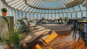 A spacious, sunlit room with a curved ceiling, furnished with chairs and tables, and featuring a view through large windows. - Cosmopolitan Bobycentrum – Czech Leading Hotels (Brno)