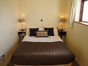 A standard hotel room with a single bed, two bedside tables with lamps, and a window with curtains. - Wards Hotel (Galway)
