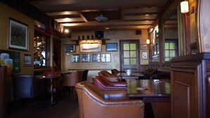Interior de un restaurante con vigas de madera, cabinas de cuero y cuadros en las paredes.