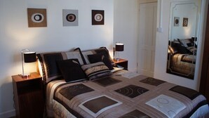 Un dormitorio con cama, dos mesitas de noche, un espejo y tres adornos circulares en la pared.
