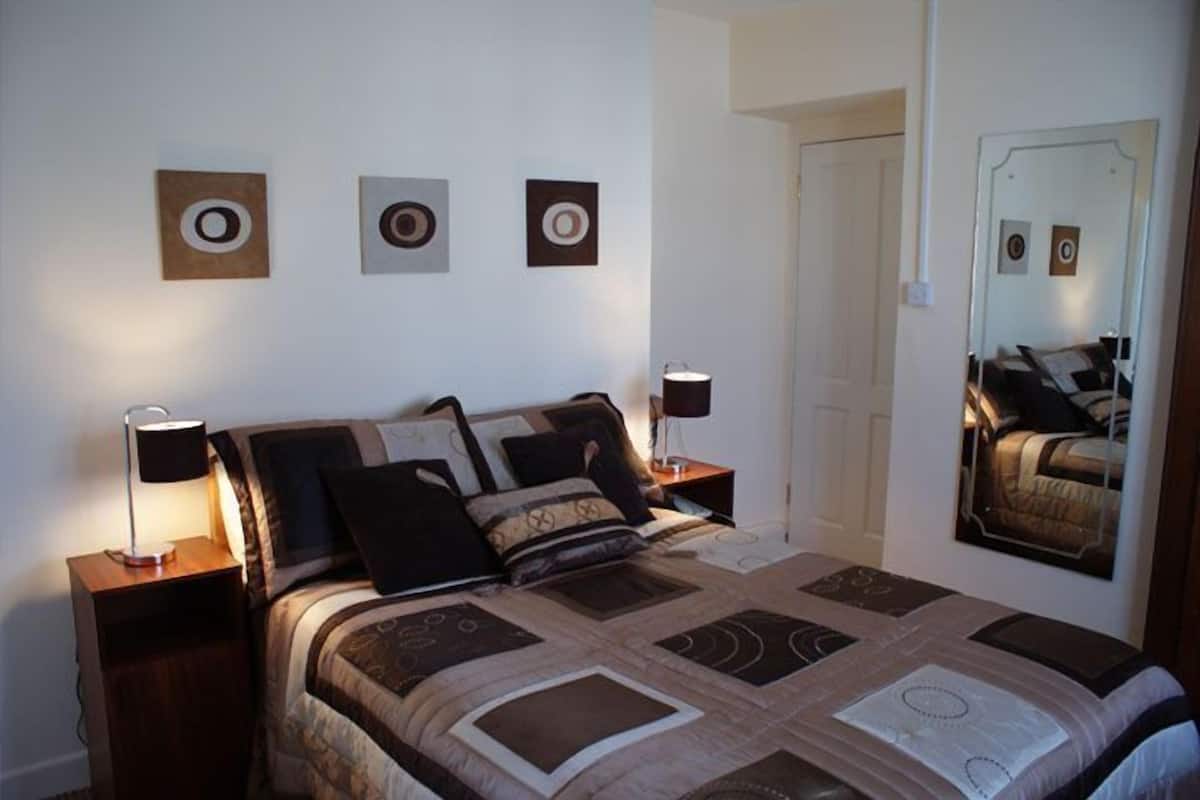 A bedroom with a bed, two bedside tables, a mirror, and three wall-mounted circular decorations.