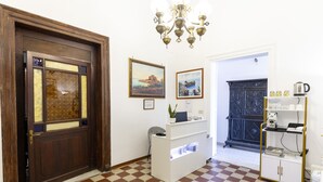 Un área de recepción con piso a cuadros, una puerta de madera, una barra blanca y un mueble negro con estantes.