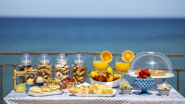 Un bufé de desayuno con diversas opciones de comida y bebidas sobre una mesa con vista al mar.