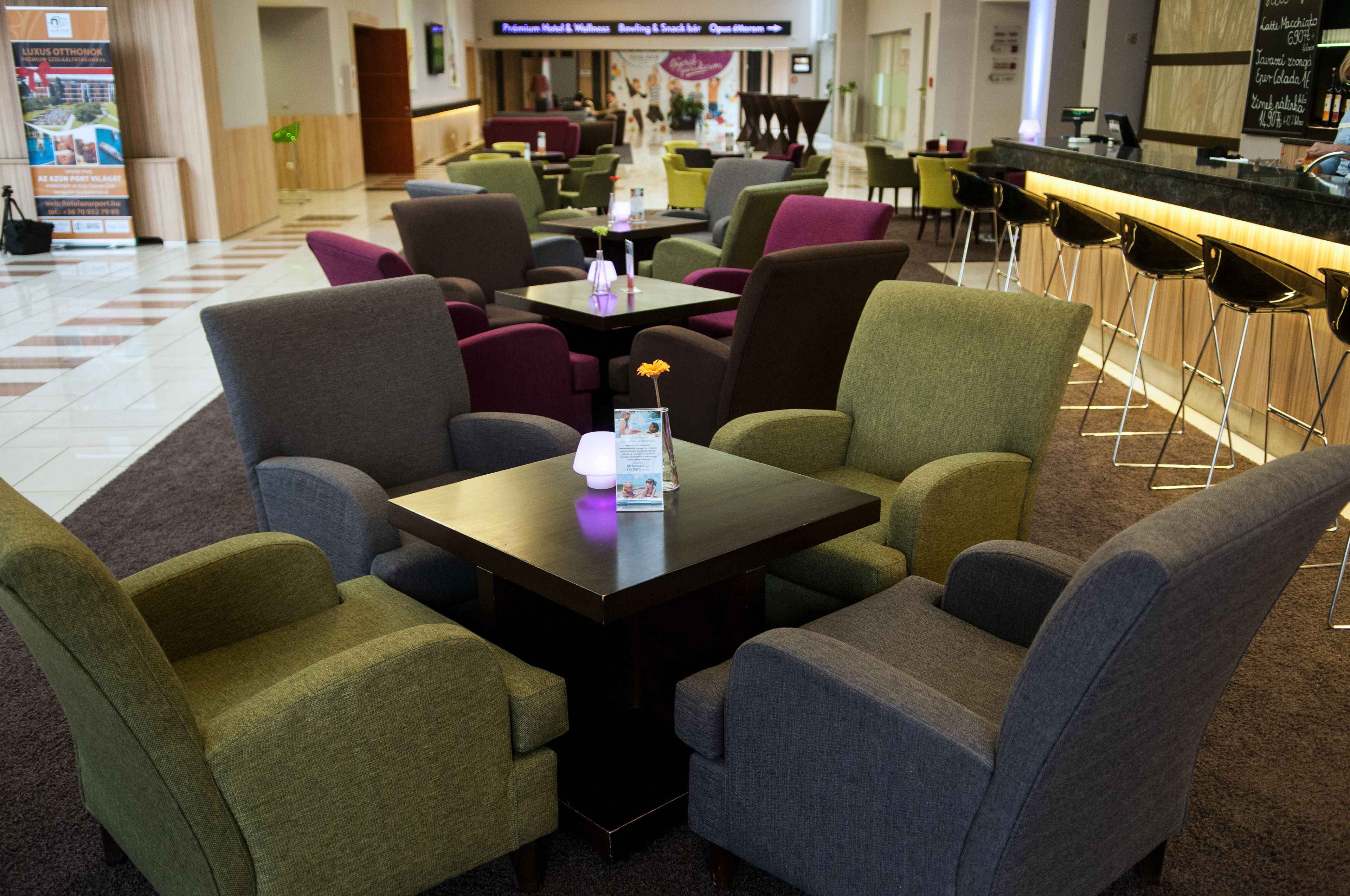 Un hall d’hôtel doté de plusieurs espaces de détente, notamment un bar avec des tabourets et un comptoir de réception.