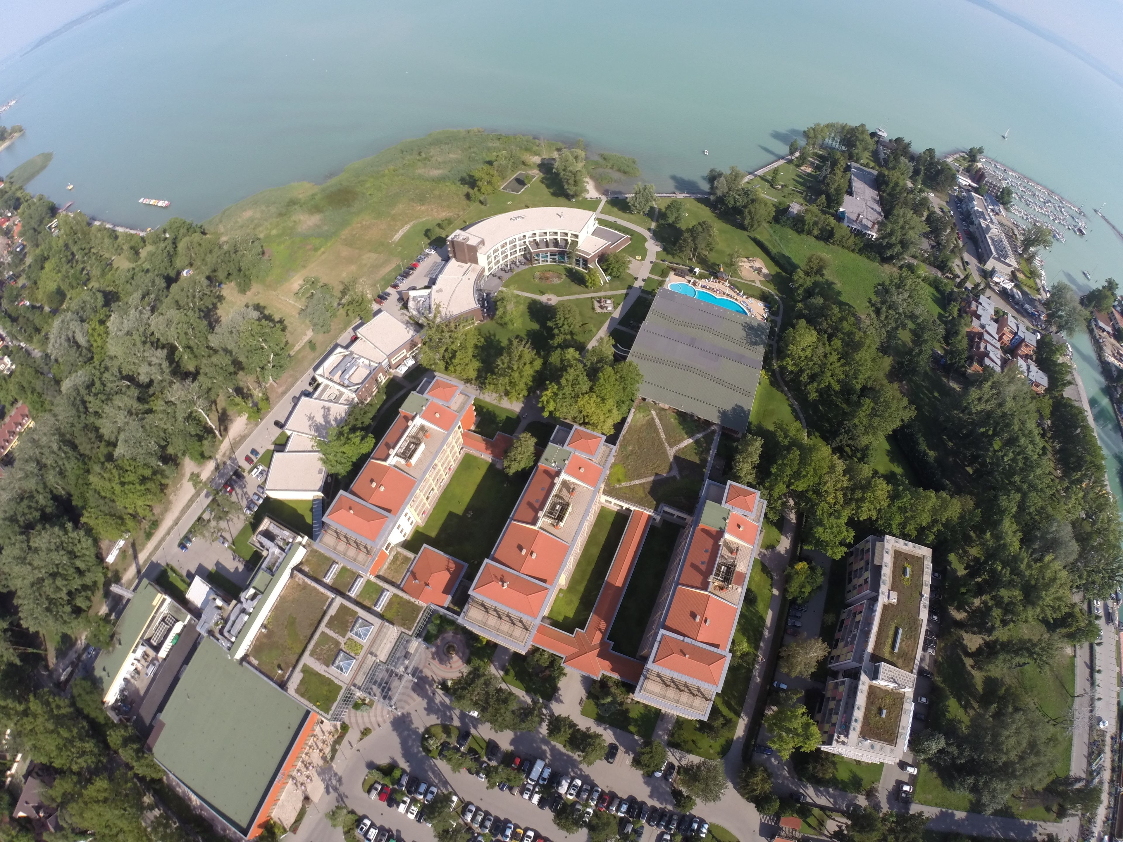 An aerial view of a campus with multiple buildings, green spaces, and a marina.