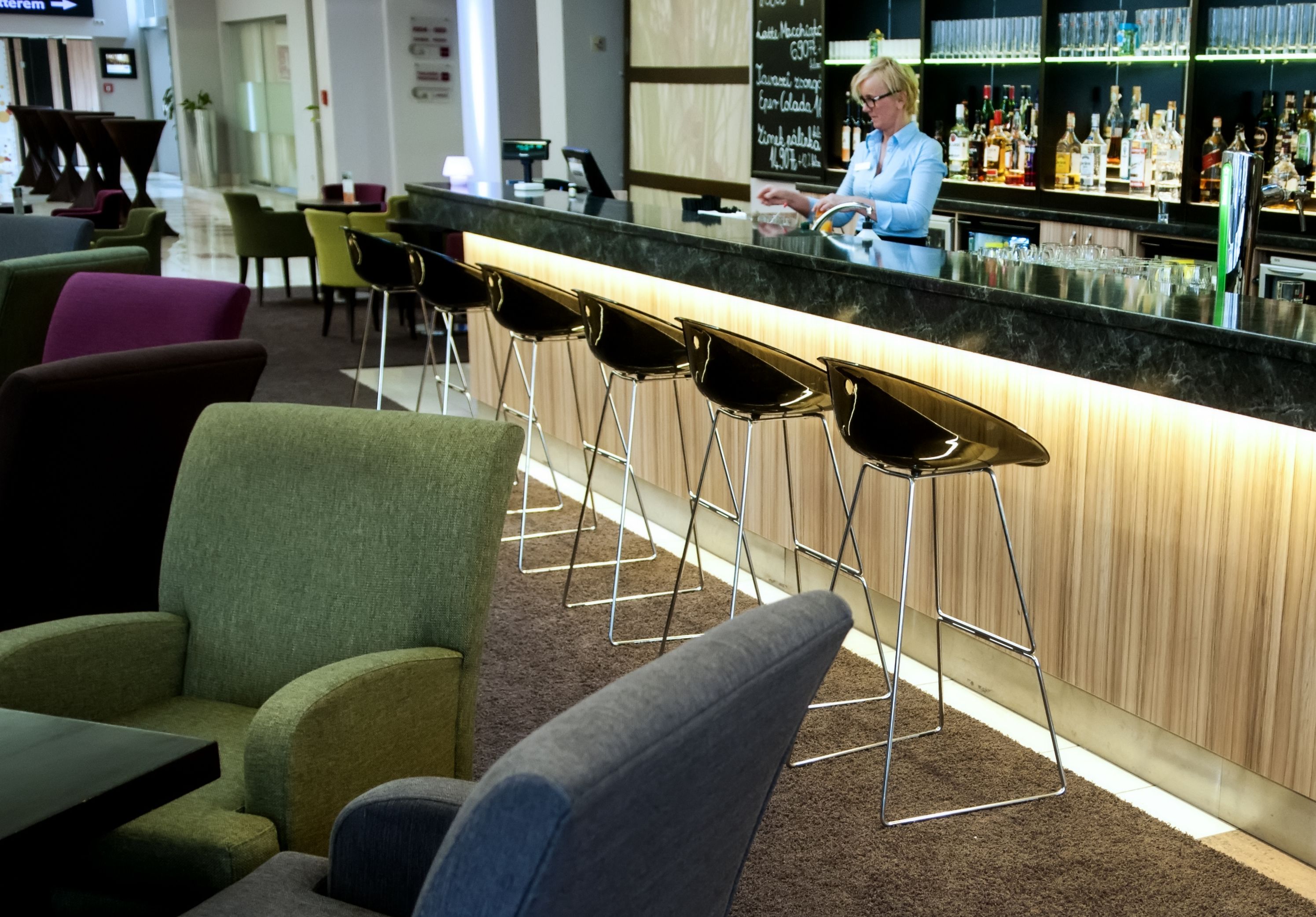 A bar area with a counter, stools, and a bartender.