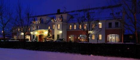 A large, multi-story building with a prominent entrance, several windows, and a snow-covered ground.