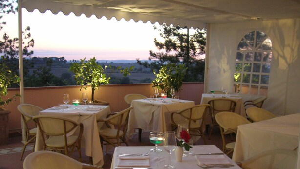 Ein Restaurant mit gedeckten Tischen, Außenbereich und Blick auf die Landschaft.