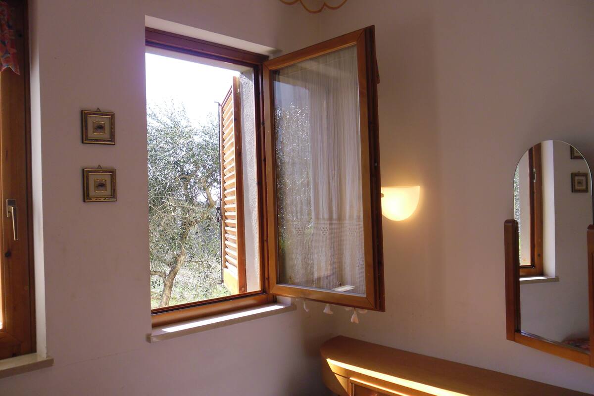 A room with a window, a mirror, and two framed pictures on the wall.
