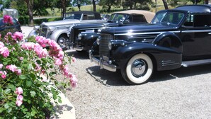 Ein klassischer schwarzer Wagen steht auf einem Parkplatz, umgeben von anderen Oldtimern.