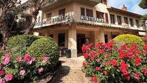 A two-story building with a sign that reads "Farneta Ristorante." There are outdoor seating areas with tables and chairs, and a pathway leading to the entrance.