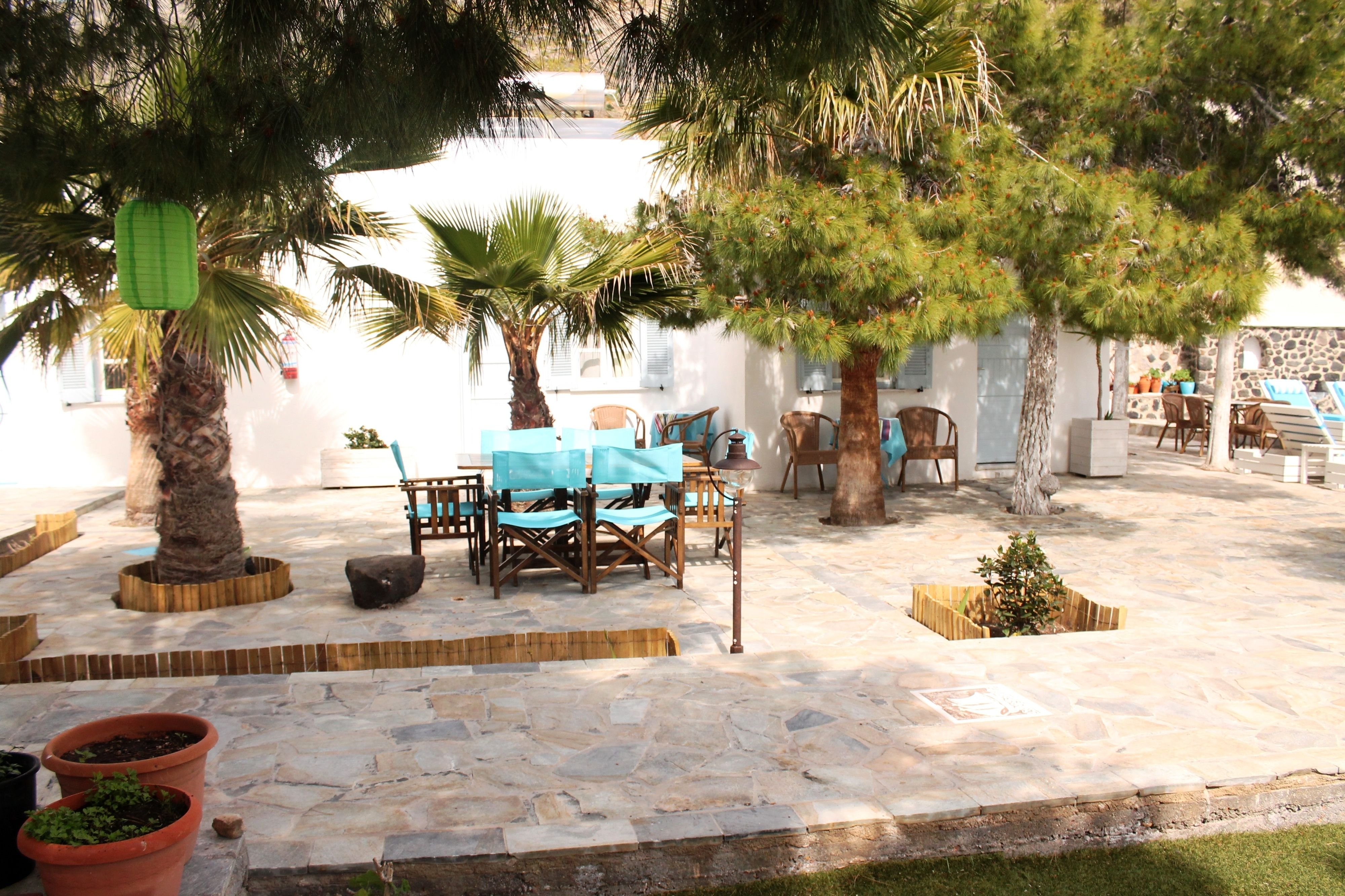 An outdoor patio area with stone flooring, wooden furniture, and potted plants.