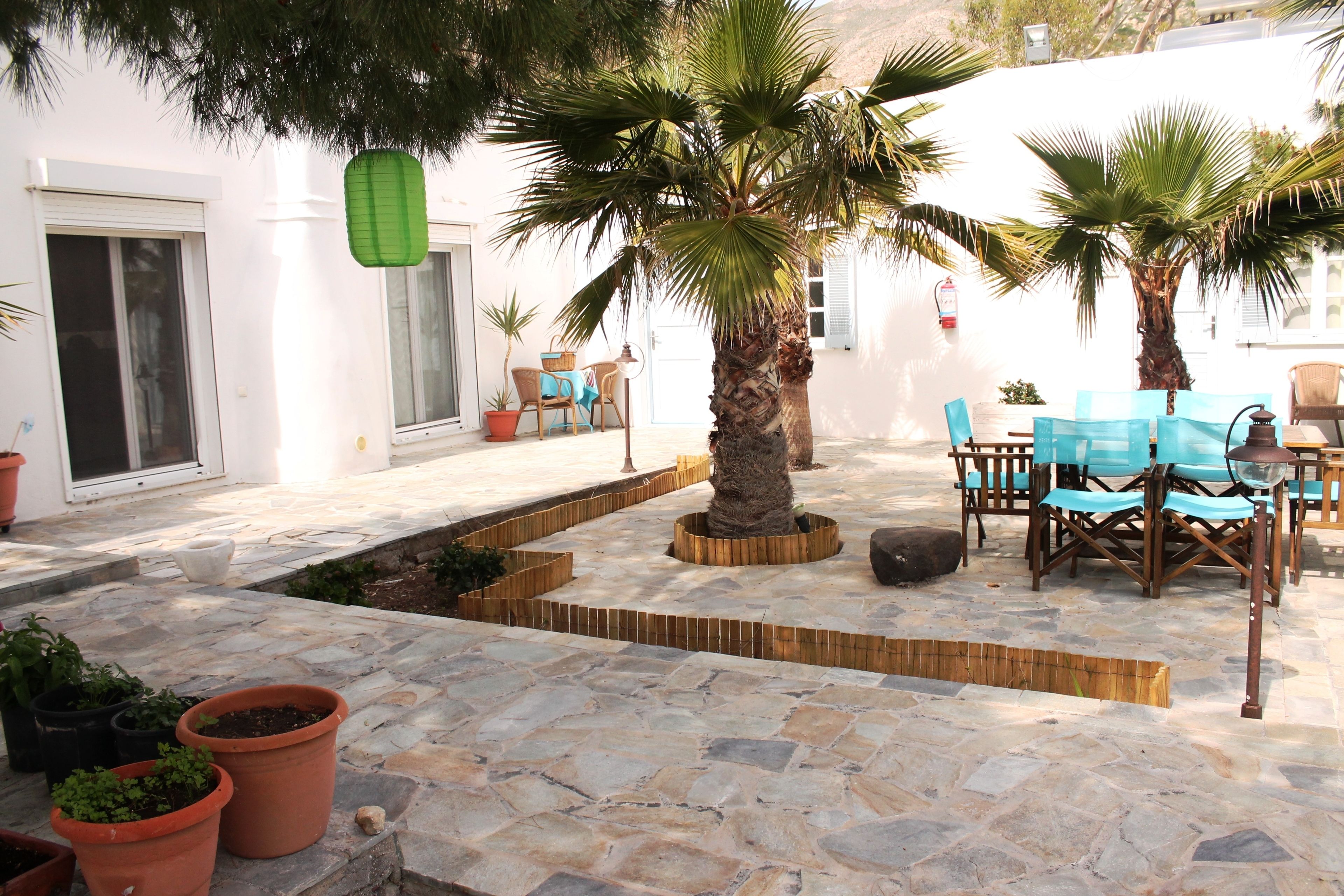An outdoor patio area with stone flooring, potted plants, and outdoor furniture.
