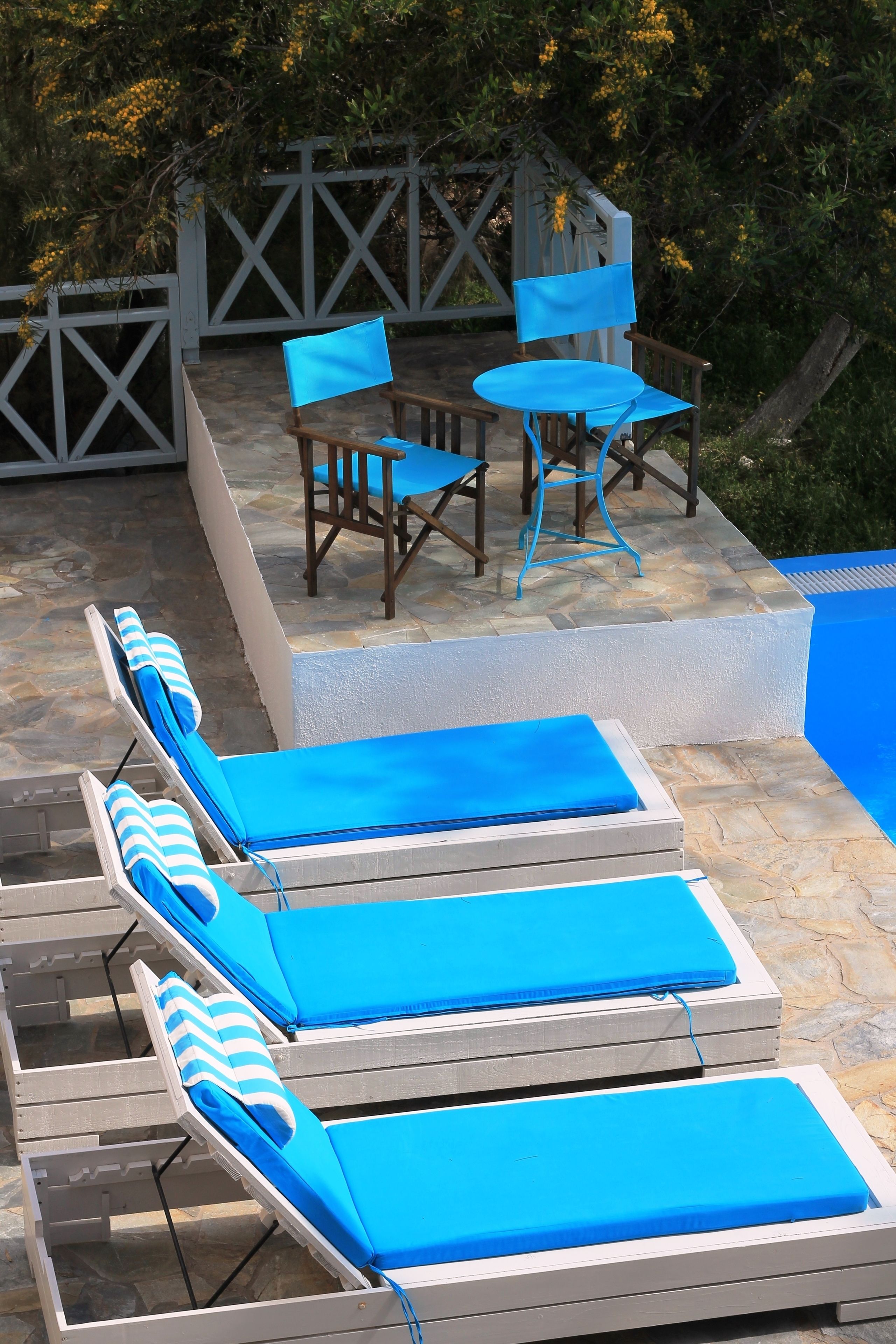 Un espace aménagé au bord de la piscine, avec des chaises longues et une table.