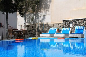 Una piscina al aire libre, sombrillas, tumbonas