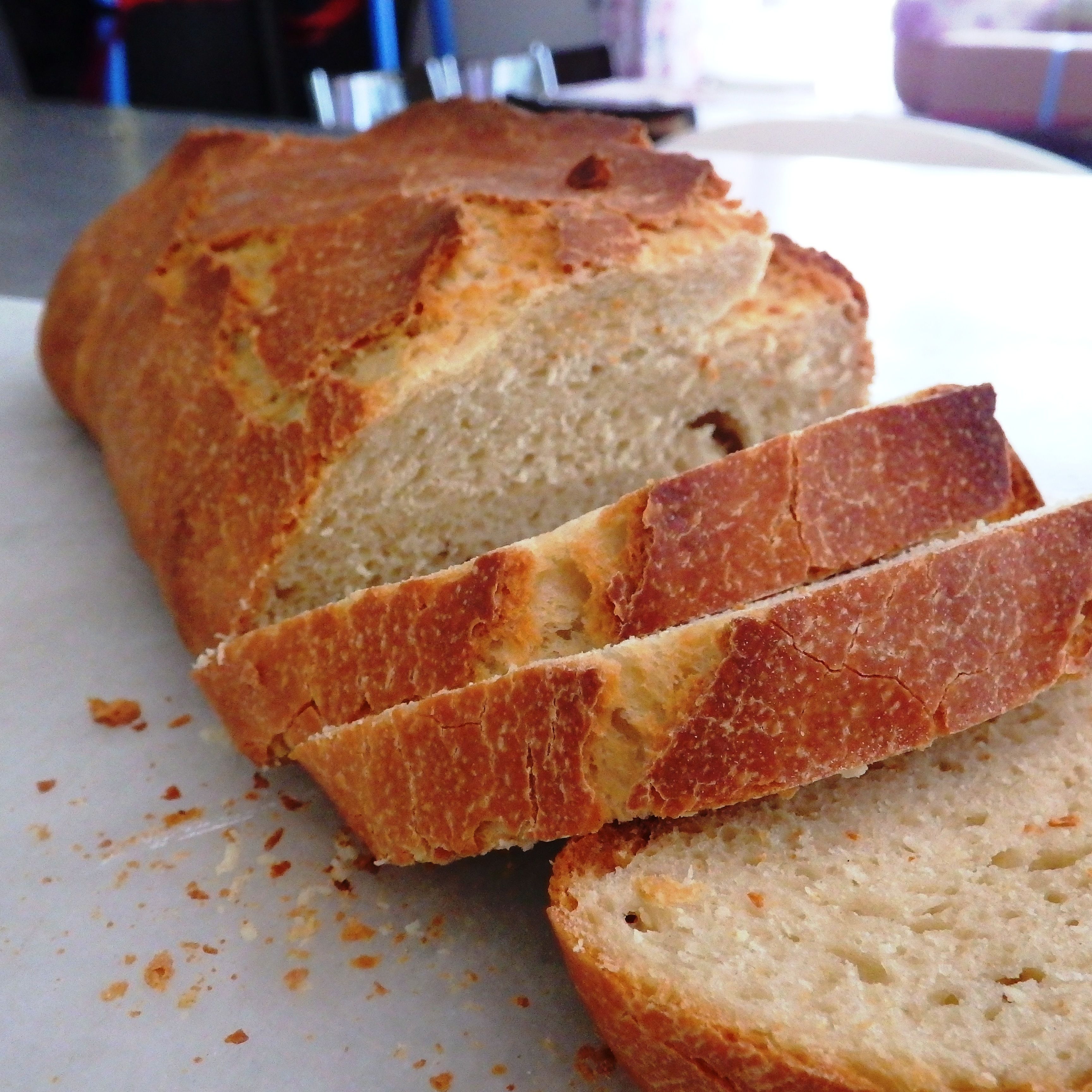Une miche de pain à la croûte croustillante et à la mie moelleuse, coupée en tranches.