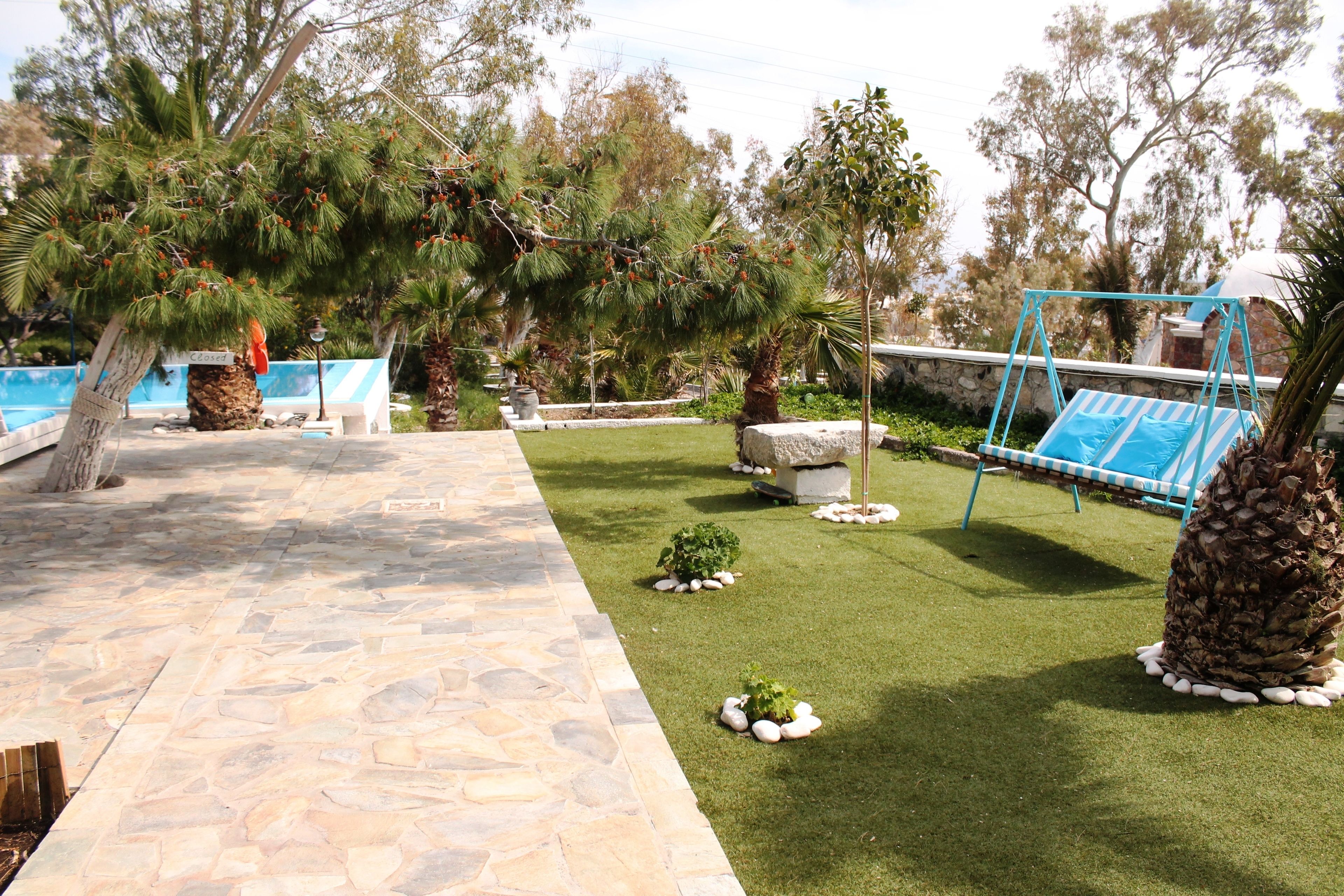 A stone pathway leading to a pool area with a swing set and palm trees.