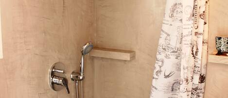 A shower area with a showerhead, handheld shower, and a curtain with printed designs.