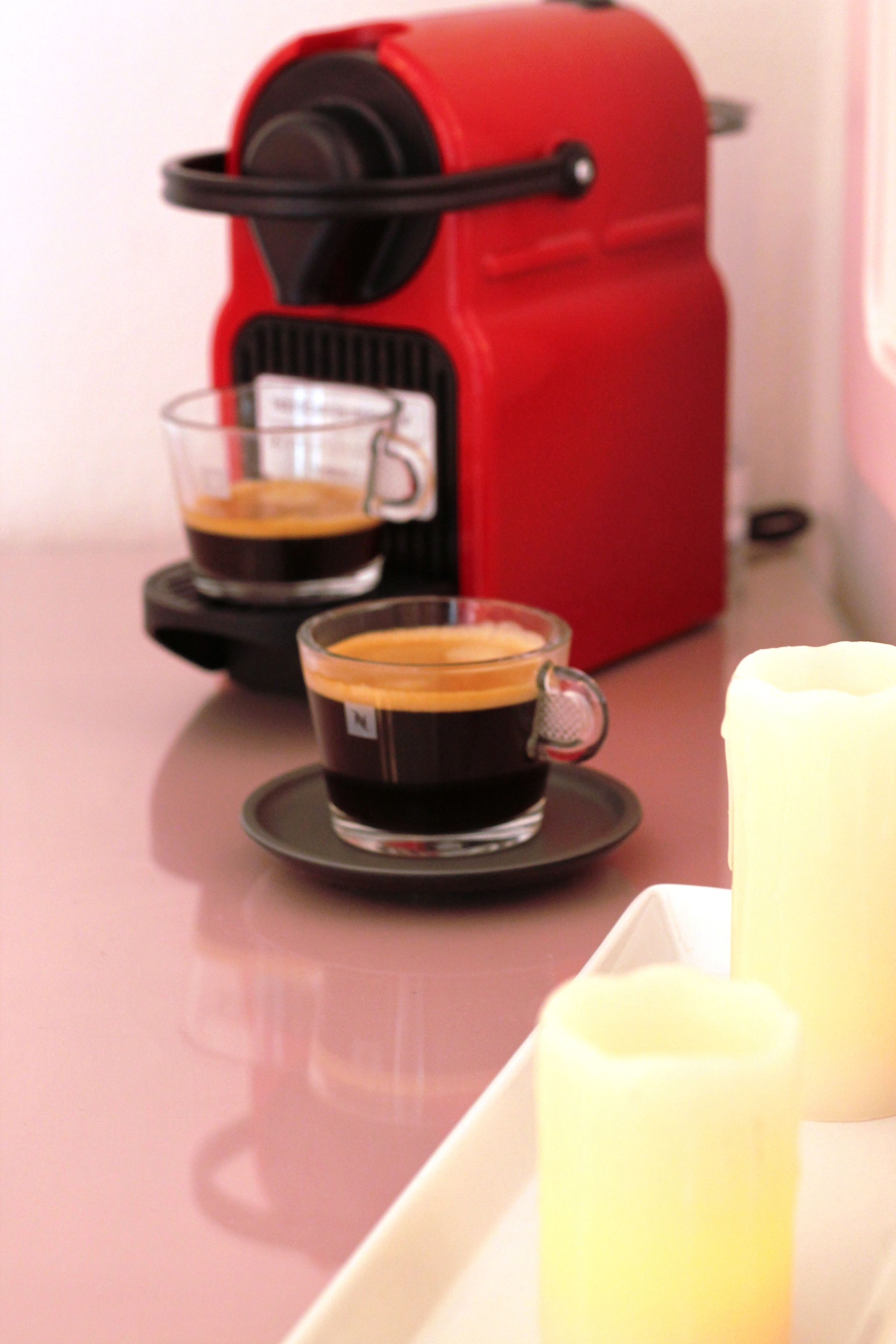 Une machine à expresso rouge avec deux tasses de café posées sur un plateau.