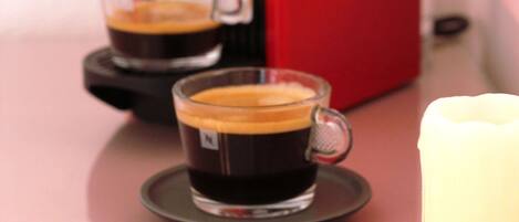Une machine à expresso rouge avec deux tasses de café posées sur un plateau.