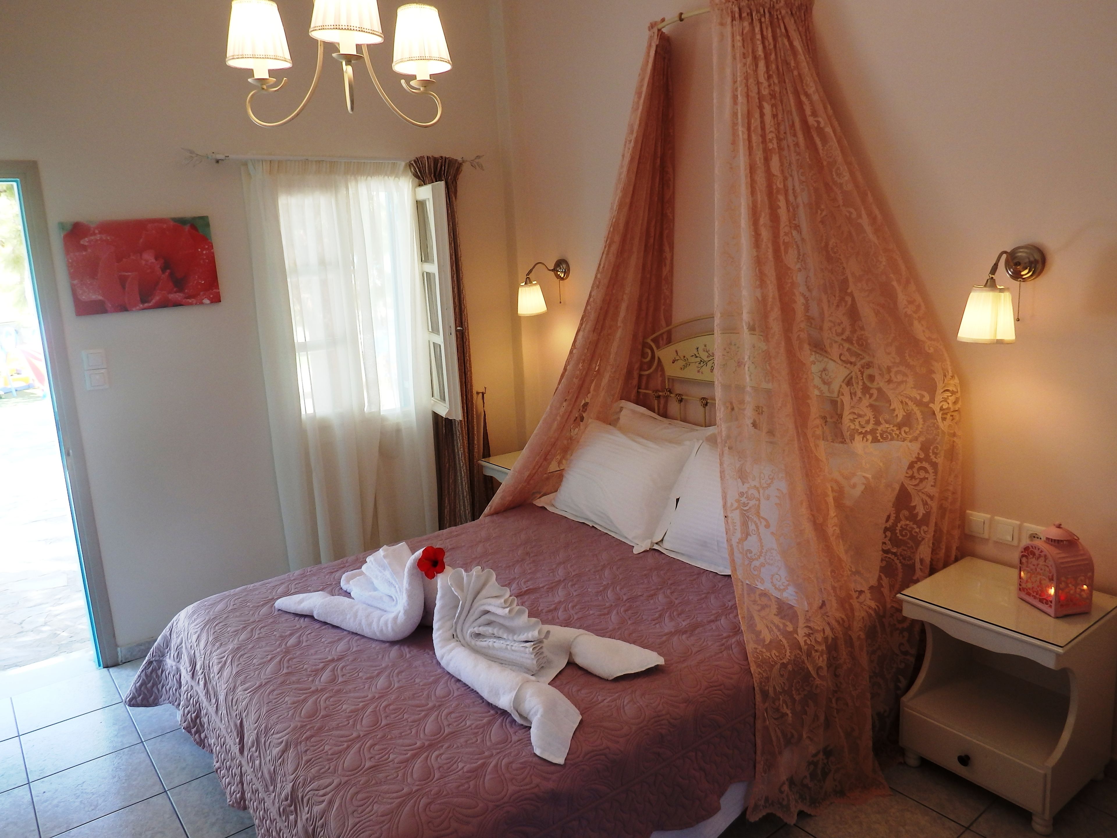 Ein Schlafzimmer mit Baldachinbett, Nachttischlampen, einem Nachttisch und einem roten dekorativen Element an der Wand.