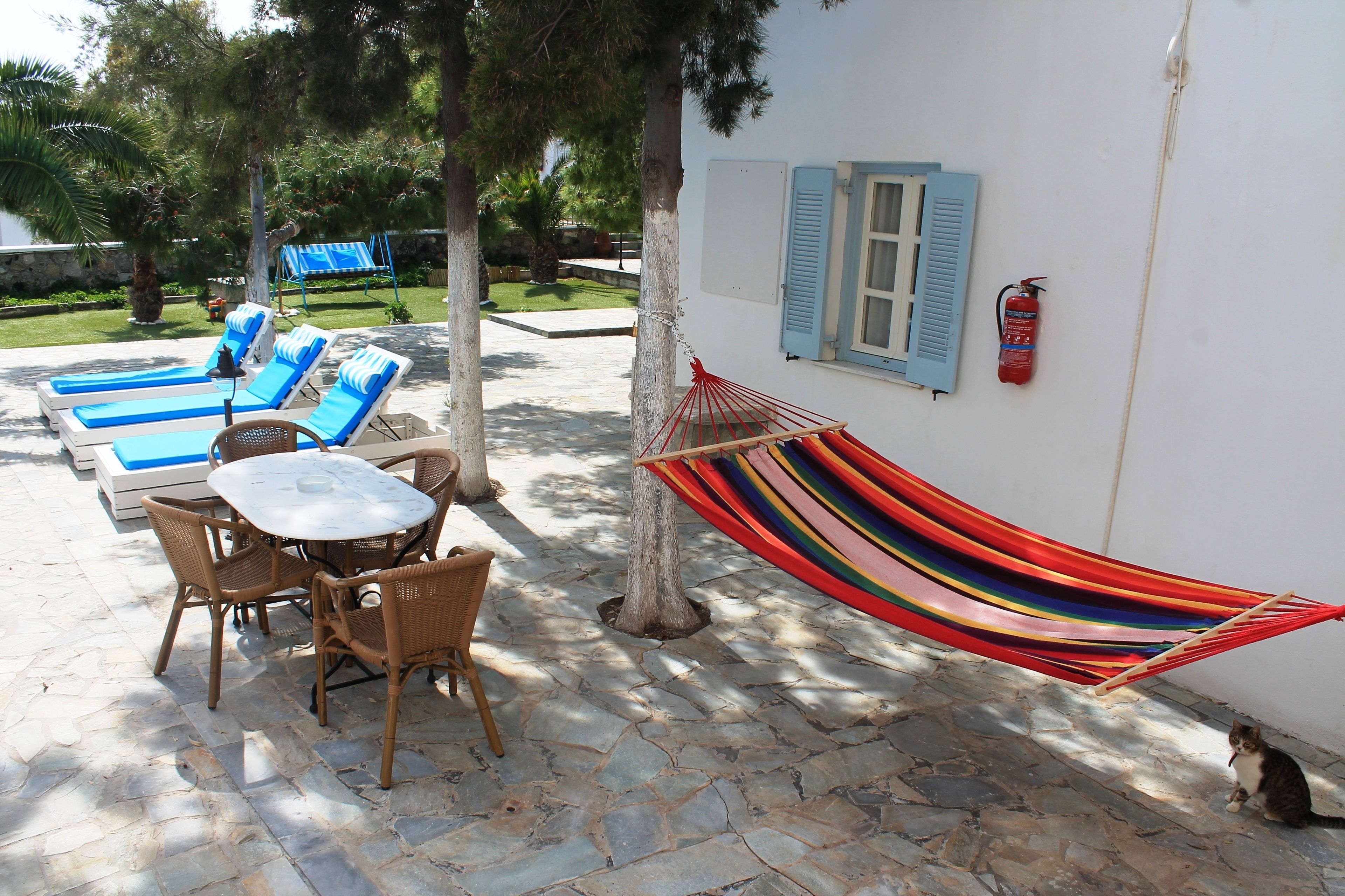 A patio with lounge chairs, a table, and a hammock.