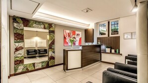A reception area with a stone wall, a reception desk, and seating. - Hotel Rinascimento  (Rome)