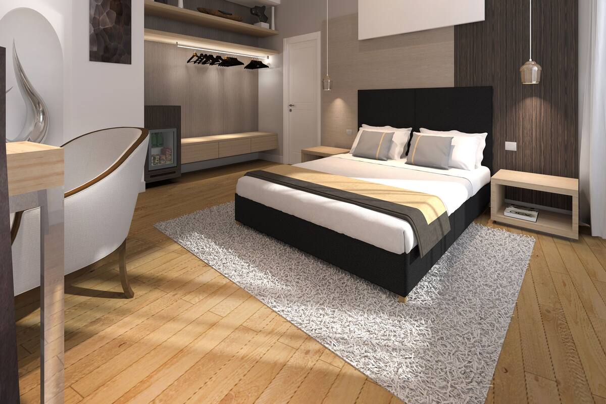 A modern bedroom with a bed, bedside tables, a chair, a desk, and built-in shelving with shoes.