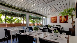 A restaurant with tables set for dining, potted plants, and artwork on the walls. - Hotel Rinascimento  (Rome)