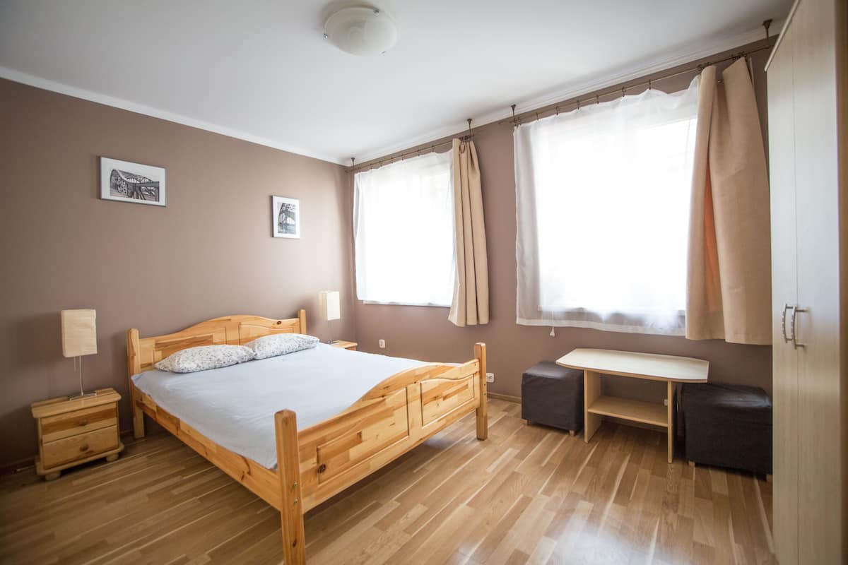 A bedroom with a wooden bed, bedside tables, a desk, and a wardrobe.