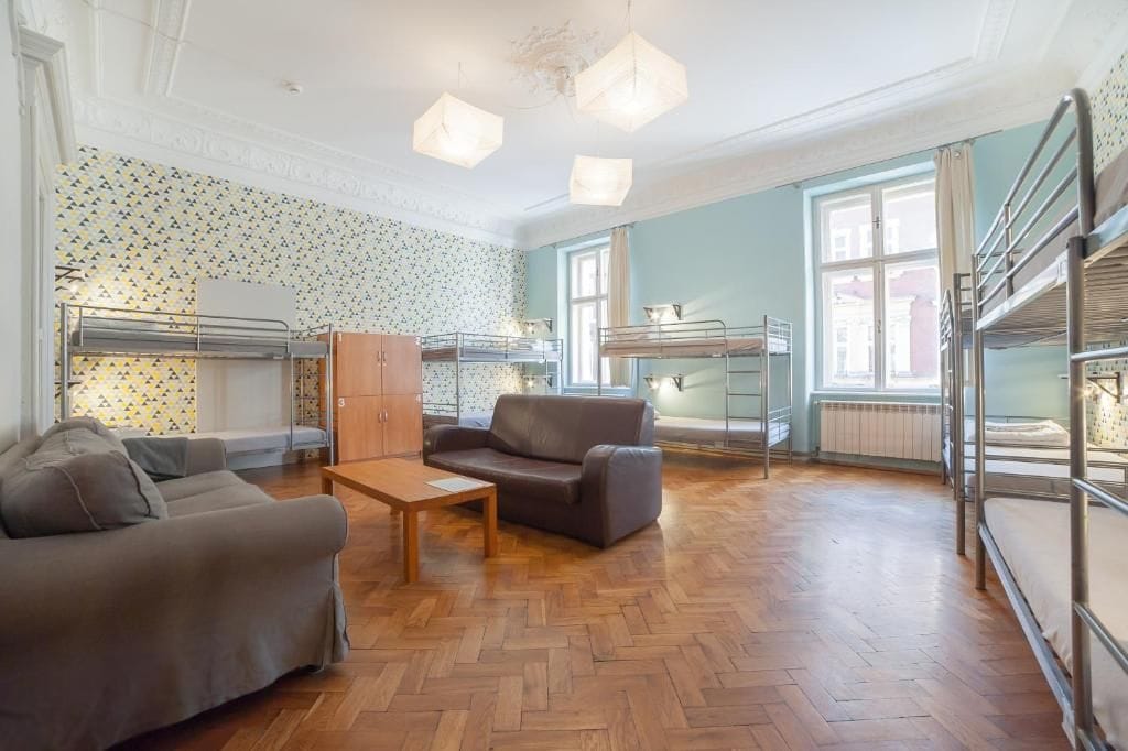 A room with bunk beds, a sofa, a table, and a patterned wallpaper.