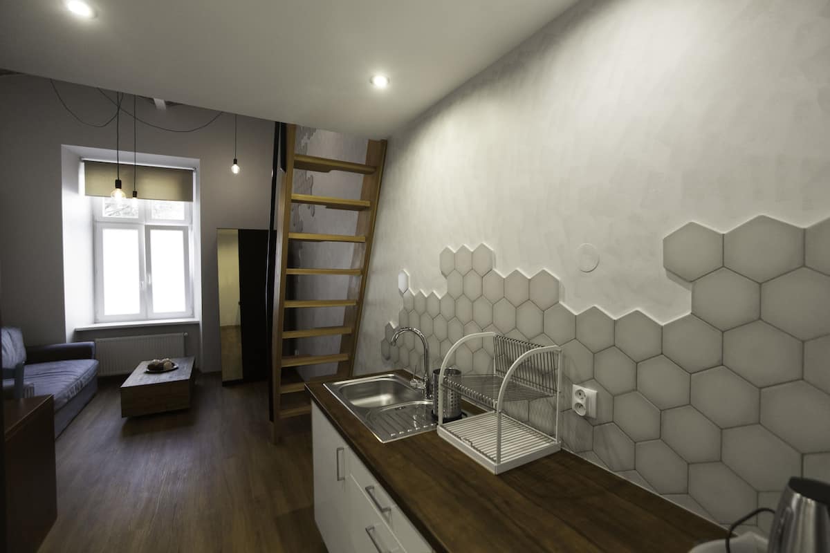 A modern kitchen with a wooden countertop, a built-in sink, and a hexagonal tile backsplash.